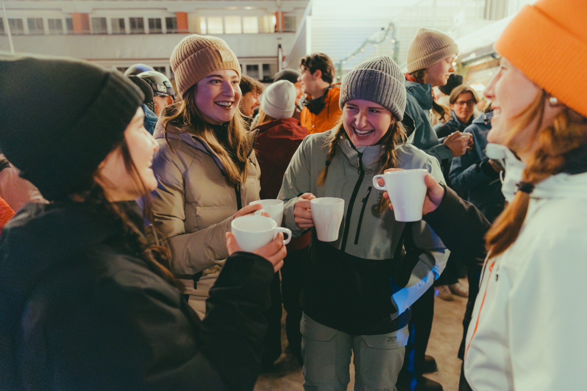 Gruppe in Wintersachen steht zusammen und hält Becher in der Hand