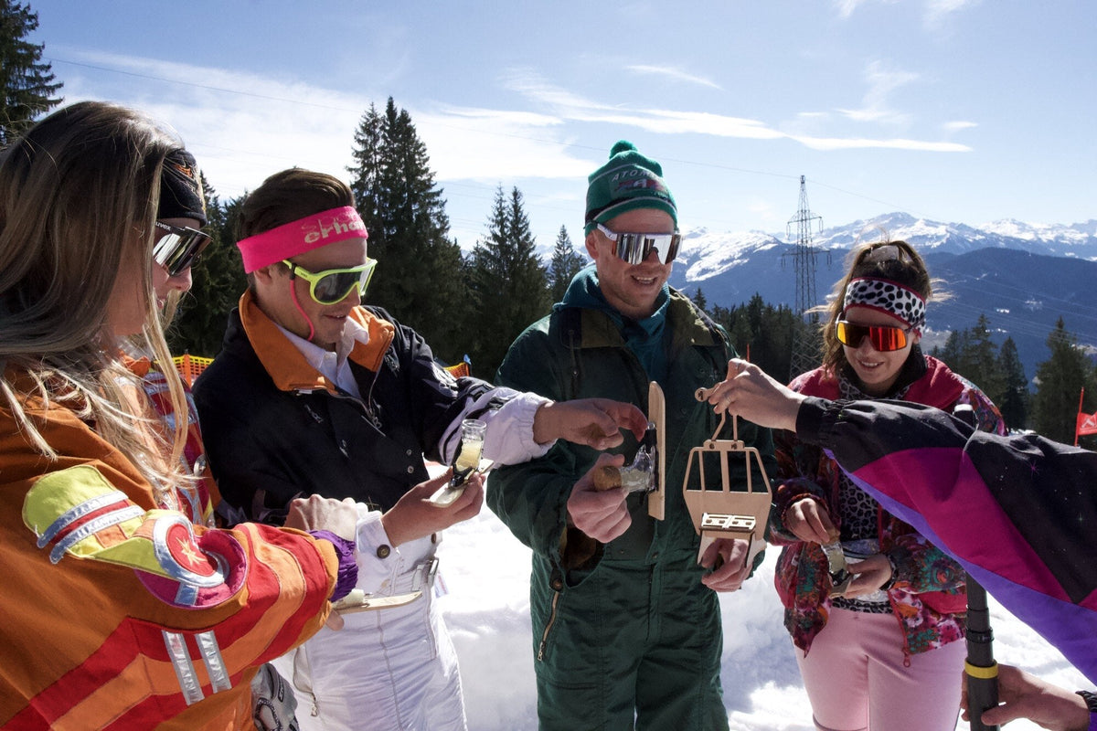 Retro-Skifahrer kippen gleichzeitig Shots aus Holzgläschen, Untersicht vor Schnee