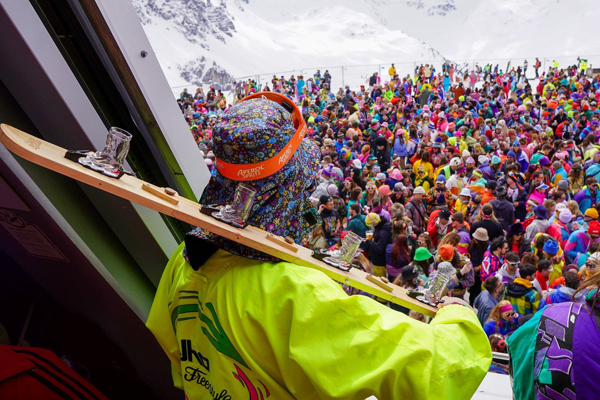 Apres-Ski: Wintersportler stoßen mit Jagertee vor einer Berghütte an