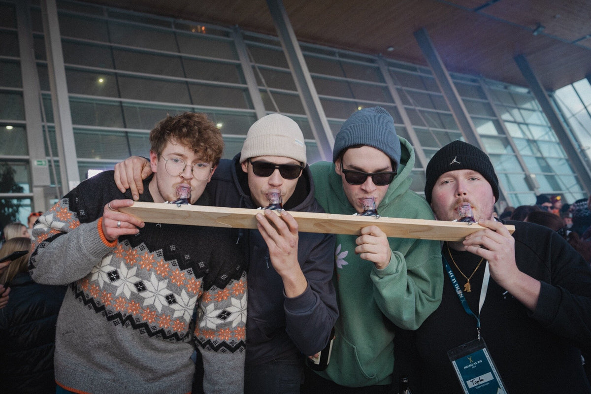 Vier Freunde trinken gemeinsam aus dem langen Apres-Allstars-Shotski mit Schnapsstiefeln