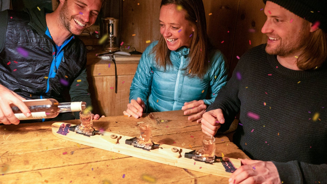 Karneval-Trinkspiele: Runde am Tisch stößt mit Shotski an, Konfetti fliegt