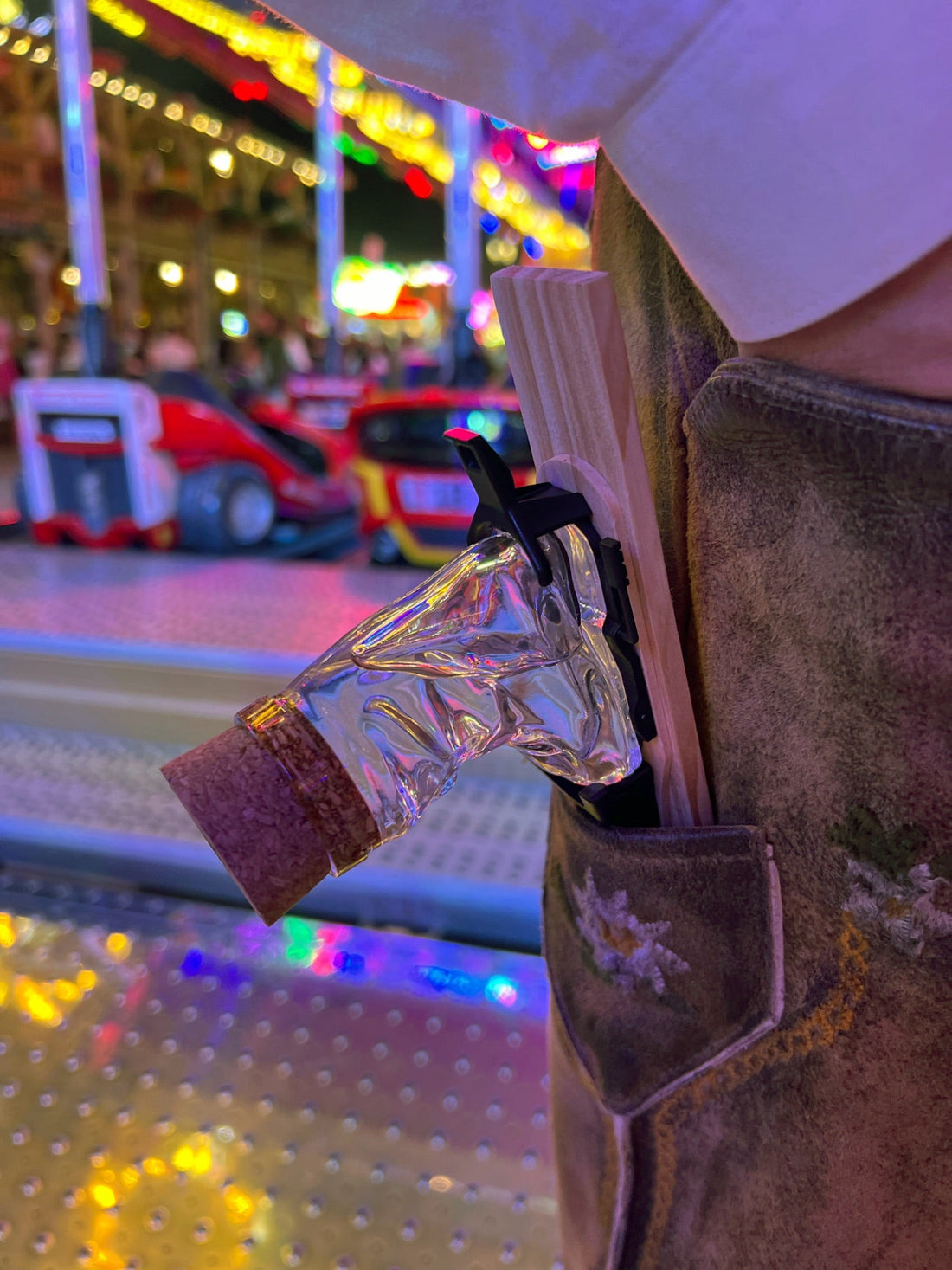 Skischuh-Schnapsglas am Band, eingesteckt in eine Lederhosen-Tasche auf dem Volksfest