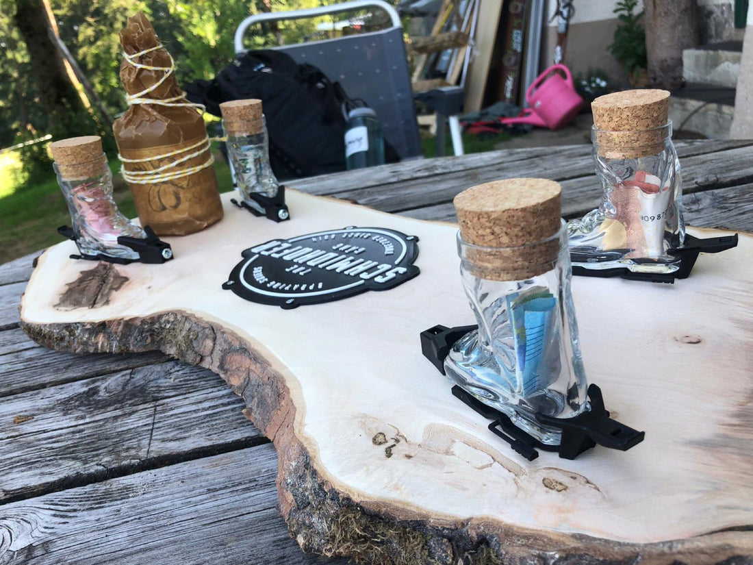 Skischuh-Schnapsgläser mit Geldscheinen gefüllt auf einem Holzbrett im sommerlichen Garten