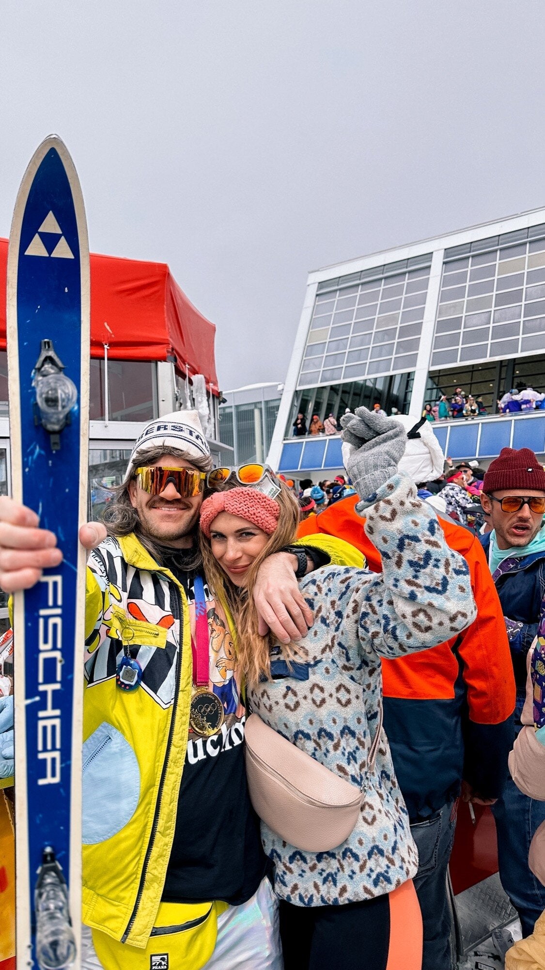 Paar in bunten Retro-Skijacken an der Gondelstation — Trinkspiele fuer Paare beim Apres-Ski