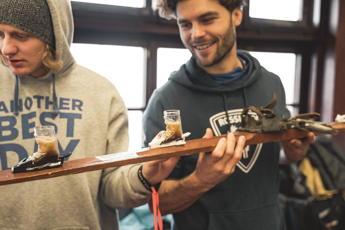 Zwei Maenner halten lachend einen Shotski — Trinkspiele zu zweit fuer das Duell