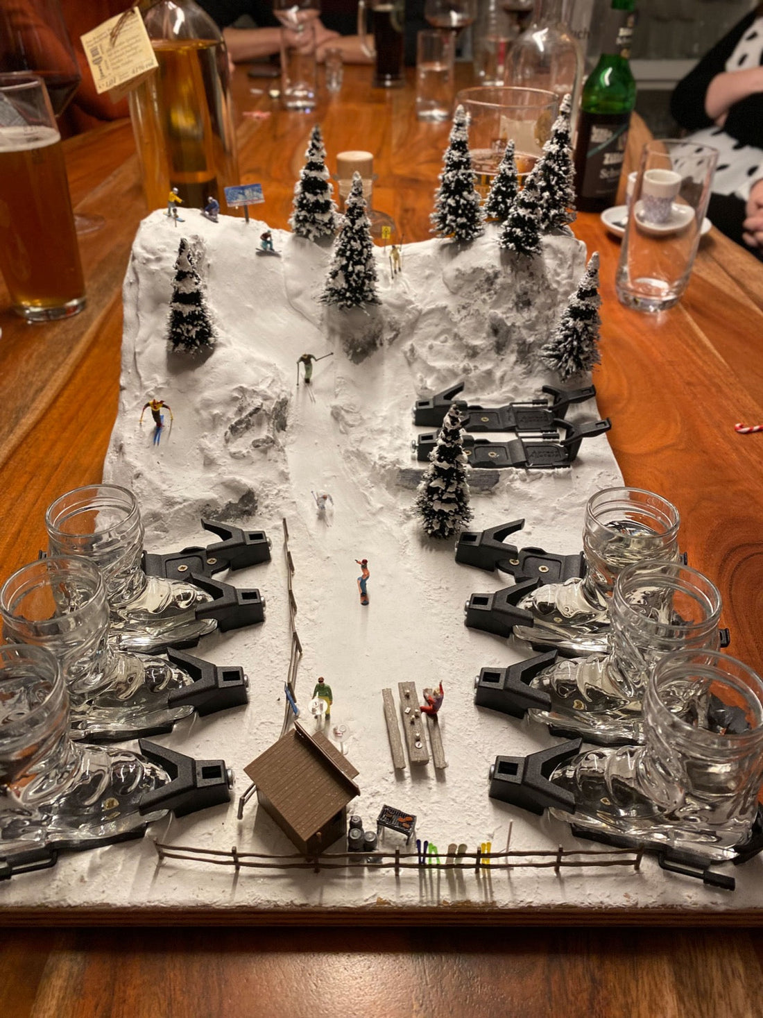 Winterlandschaft als Tischdeko mit Tannen, Skifahrern und Skischuh-Shotgläsern in Bindungen