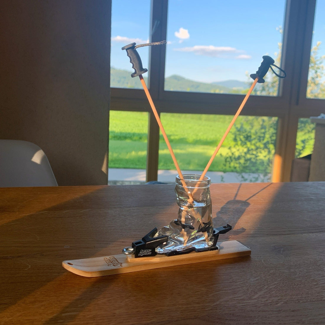 Miniski mit Skischuh-Glas und zwei Mini-Skistöcken als Duftstäbchen im Zirben-Flakon auf einem Holztisch