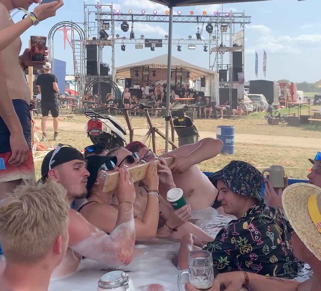 Festival-Gruppe glüht im Pool vor der Bühne vor und trinkt gemeinsam vom Shotski
